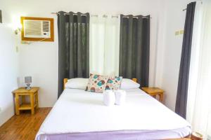 um quarto com uma cama branca e cortinas pretas em Baki Divers and Beach Resort em Dauin
