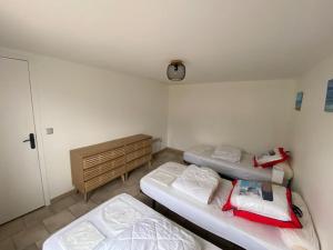 a room with three beds and a clock on the wall at Maison de vacances in La Cotinière