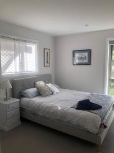 a white bedroom with a bed and a window at Danara Cottage in Bathurst