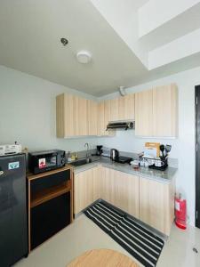 a kitchen with wooden cabinets and a black refrigerator at * * WV 1 Minimalist Studio in Iloilo City