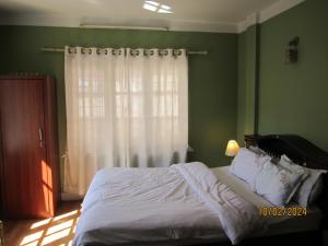 1 dormitorio con 1 cama con sábanas blancas y ventana en KAJI HOME, en Pātan
