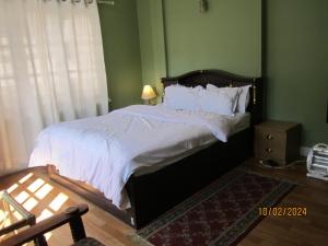 1 dormitorio con 1 cama grande con sábanas blancas en KAJI HOME, en Pātan