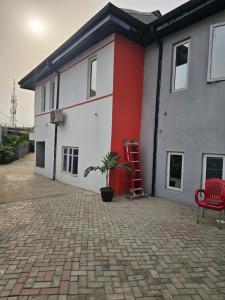 a building with a red ladder and a plant in front of it at Hencapservices 001HPS in Agege