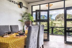 Kinigi Cottage في Kinigi: غرفة طعام مع طاولة وكراسي ونافذة