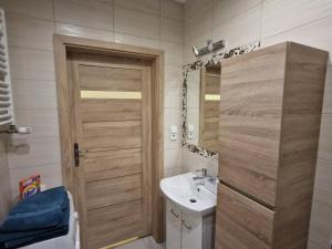 a bathroom with a wooden door and a sink at Apartament morski Aquasfera in Reda
