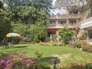 un jardín frente a un edificio con sombrilla en The Estate Villa, en Nueva Delhi
