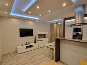 a living room with a kitchen with a tv on the ceiling at Apartament morski Aquasfera in Reda