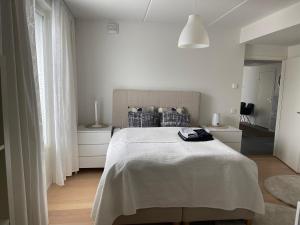 Upea 117,5m2 huoneisto Helsingin keskustassa في هلسنكي: غرفة نوم بيضاء بسرير وليلتين