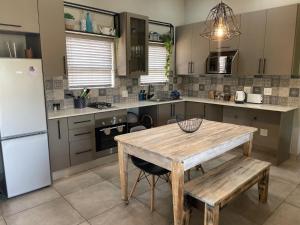 a kitchen with a wooden table and a refrigerator at The Lodge on Ilona in Tierpoort