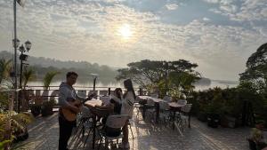 Ein Mann spielt Gitarre auf einer Terrasse mit einer Frau in der Unterkunft Day Waterfront Hotel in Chiang Khong