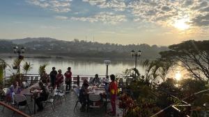 eine Gruppe von Menschen, die an Tischen in der Nähe eines Flusses sitzen in der Unterkunft Day Waterfront Hotel in Chiang Khong