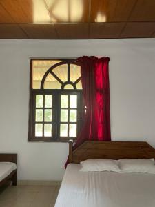 1 dormitorio con ventana y cortina roja en Bhawana Canal View Resort, en Nochchiyagama