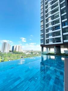 a swimming pool in front of a tall building at The Emerald Golf View in Thuan An