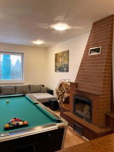 a living room with a pool table and a brick fireplace at Vila Lesana in Nová Lesná
