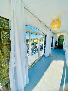sala de estar con cortinas blancas y balcón en Villa Montalbo vue mer de 2 à 10 personnes, en Cargèse