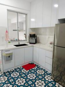 una cucina con armadi bianchi e un tappeto rosso sul pavimento di Embun Bayu Musliim homestay a Rawang