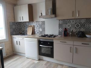 La cuisine est équipée de placards blancs et d'un four avec plaques de cuisson. dans l'établissement Maison au calme à Saint-Brieuc, à Saint-Brieuc