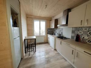 une cuisine avec des placards blancs, une table et une fenêtre dans l'établissement Maison au calme à Saint-Brieuc, à Saint-Brieuc
