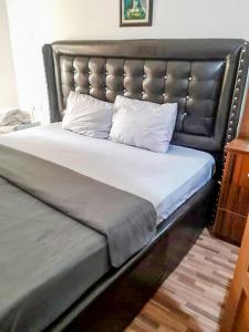 1 cama grande con cabecero de cuero y 2 almohadas en Gifted Apartment & Residence, en Abuja