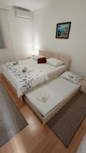 two twin beds in a room with wooden floors at Apartment Relax in Mokošica