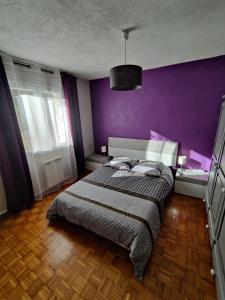 - une chambre dotée d'un lit avec un mur violet dans l'établissement appartement avec vue panoramique, à Combaillaux