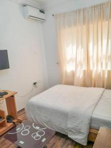 a bedroom with a bed and a desk and a window at Gifted Apartment & Residence in Abuja