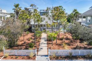 une maison avec une clôture blanche devant une cour dans l'établissement The Cottage, à Santa Rosa Beach