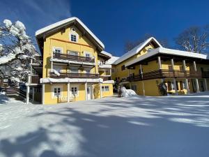 ein gelbes Gebäude mit Schnee davor in der Unterkunft St Lukas Apartments in Oberammergau