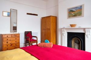 um quarto com uma cama vermelha e uma lareira em Bright, character 3 bed Apartment: 7 mins walk to sea em Portsmouth