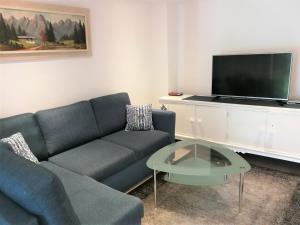 a living room with a blue couch and a tv at St Lukas Apartments in Oberammergau