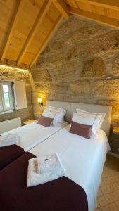two beds in a room with a stone wall at Quinta da Cumieira Nova in Seia