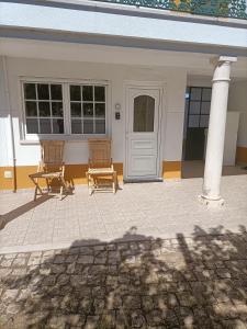 une maison avec deux chaises devant une porte dans l'établissement Family House Cup- Quinta das Pinheirinhas, à Tomar