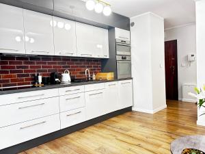 una cucina con mobili bianchi e un muro di mattoni di Rydygiera14 a Breslavia