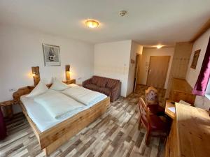 1 dormitorio con 1 cama, 1 sofá y 1 silla en Gasthof zum Lowen, en Aschau