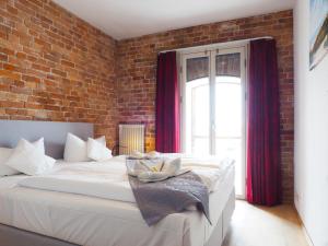 um quarto com uma grande cama branca e uma parede de tijolos em Speicher Barth - Superior-Hotel em Barth
