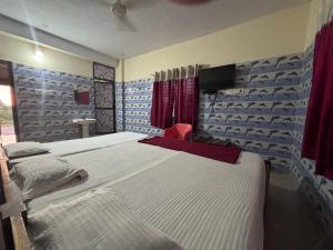 - une chambre avec 2 lits et une télévision murale dans l'établissement Naika Lodge, à Māvalli