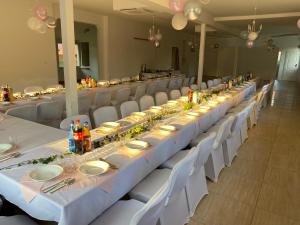 um longo salão de banquetes com mesas brancas e cadeiras brancas em Agroturystyka E.KO 