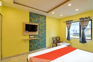 a bedroom with a bed and a tv on a yellow wall at Hotel Divine Chariot in kolkata