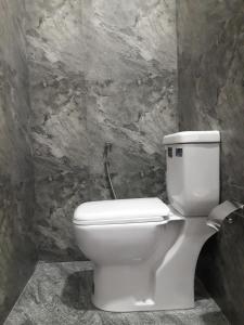 a white toilet in a bathroom with a stone wall at Harmonic villa in Weligama