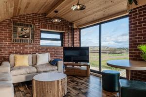 a living room with a couch and a tv and a brick wall at Brick Barn - Luxury Barn Conversion by River Avon! in Cropthorne