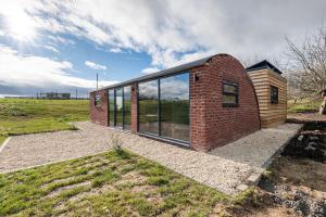 a brick house with glass windows on a field at Brick Barn - Luxury Barn Conversion by River Avon! in Cropthorne