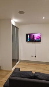 a living room with a couch and a flat screen tv on the wall at London Tottenham Stadium Apartment in London