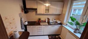 una pequeña cocina con armarios blancos y fregadero en Apartament na Bałtyckiej en Kołobrzeg