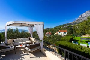 a patio with a couch and an umbrella at Villa Filip Spa & Relax Makarska in Makarska