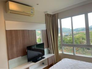 um quarto de hotel com uma televisão de ecrã plano e uma grande janela em Risa Plus2 em Kathu