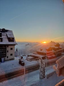 een winterscène met de zon die achter een gebouw opkomt bij Willa Sasanka in Duszniki Zdrój