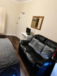 a black leather couch in a living room with a mirror at Nice and Pleasant in Thornton Heath