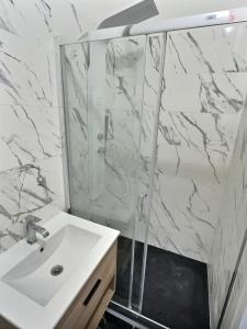a white bathroom with a sink and a shower at Appartement de charme avec balcon au pied des commerces in Béziers