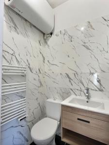 a white bathroom with a toilet and a sink at Appartement de charme avec balcon au pied des commerces in Béziers