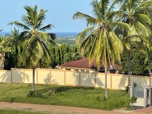 two palm trees in front of a house at Stylish 1-Bedroom Apartments with Amazing Views in Dar es Salaam